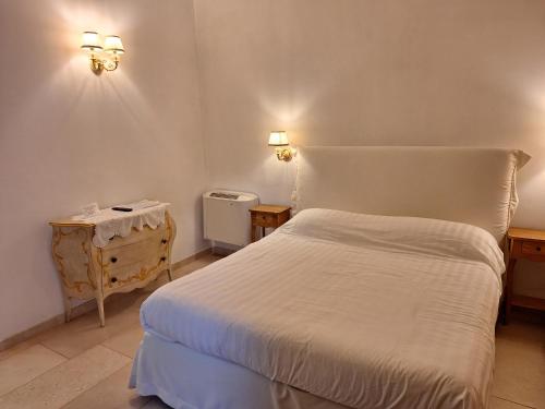 a bedroom with a white bed and two lights on the wall at Masseria Del Crocifisso in Polignano a Mare