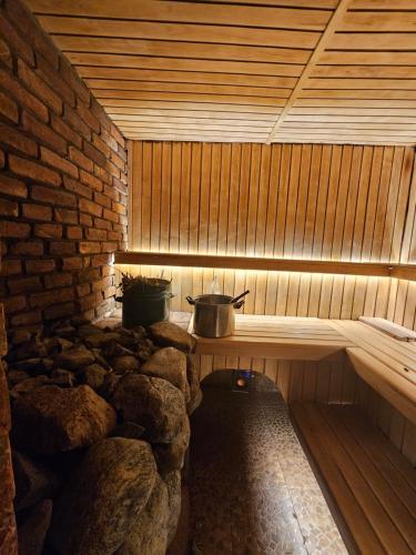 a wooden sauna with a stone wall and a pot at Svečiu Namai in Pagiriai