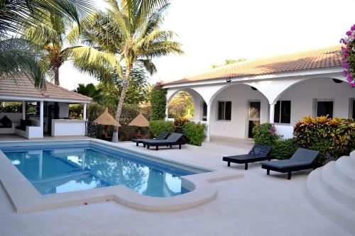 ein Pool vor einem Haus mit Palmen in der Unterkunft Chez Doki Sen hôtel in Sali Nianiaral