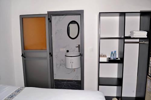 Zimmer mit einem Bett, einem Spiegel und einer Tür in der Unterkunft Chez Doki Sen hôtel in Sali Nianiaral