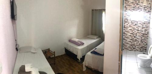 a small room with two beds and a mirror at Pousada Cactos in Chapada dos Guimarães