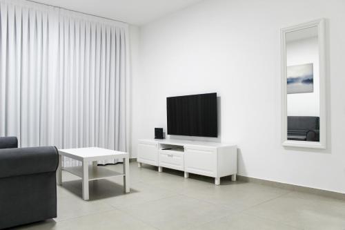 a living room with a tv on a white wall at Penthouse #47 By Hashdera Eilat in Eilat