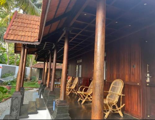 a porch of a house with chairs and a roof at Jeevan Homestay & Ayurvedic Yoga Retreat in Kovalam