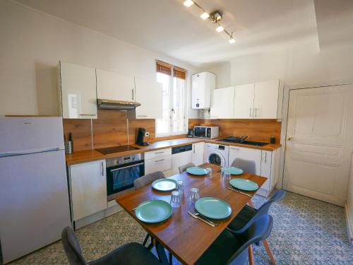 une cuisine avec une table, des chaises et un réfrigérateur dans l'établissement gîte de Saint Alban, à Saint-Alban-de-Roche