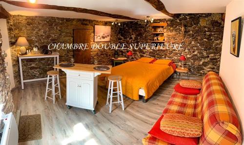 1 dormitorio con cama y mesa con taburetes en Nuits magiques au village entre mer et montagnes en Bigorno