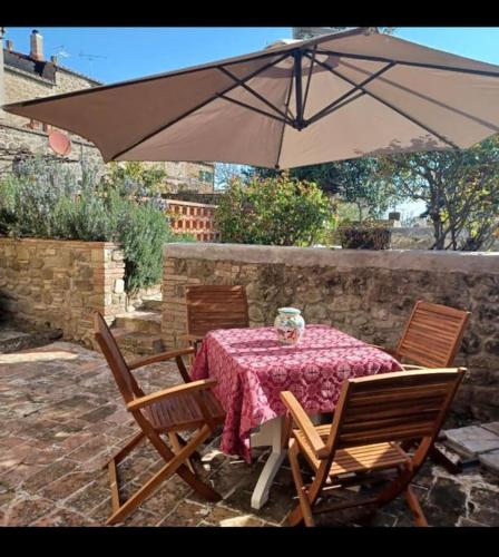 a table and chairs with an umbrella on a patio at La Casa di Orazio in Montecatini Val di Cecina
