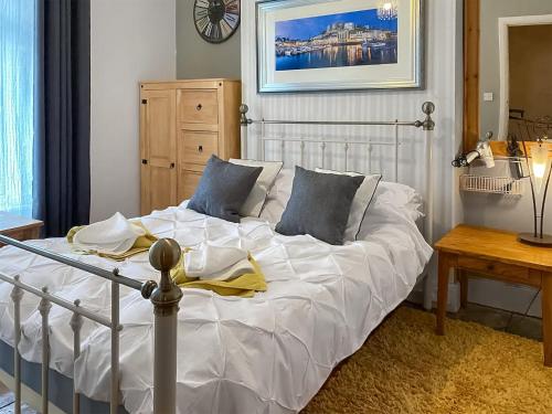 uma cama com lençóis brancos e almofadas azuis num quarto em Four-tunes em Torquay