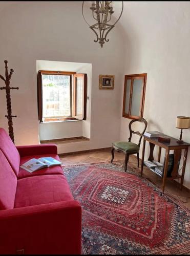 a living room with a red couch and a window at La Casa di Orazio in Montecatini Val di Cecina