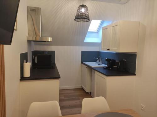 une cuisine avec des armoires blanches et un comptoir noir dans l'établissement Appartement idéalement situé proche Disneyland et Paris, à Lagny-sur-Marne