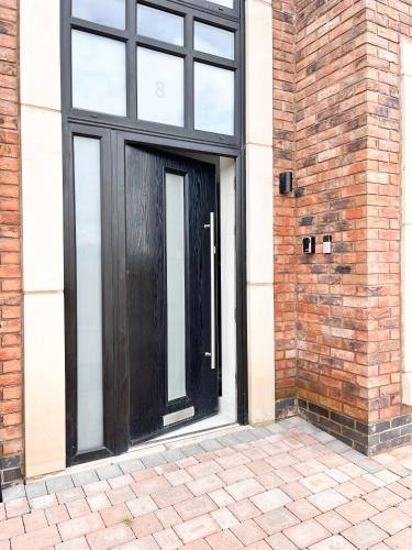 a black door on the side of a brick building at Spacious 6 bedroom House - Sleeps 11, Convenient Location, Perfect for FAMILIES in Birmingham
