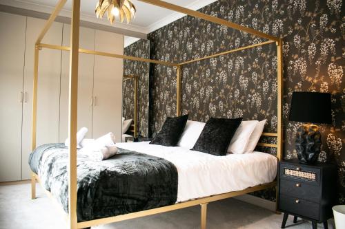 a bedroom with a canopy bed with black and gold wallpaper at Spacious 6 bedroom House - Sleeps 11, Convenient Location, Perfect for FAMILIES in Birmingham