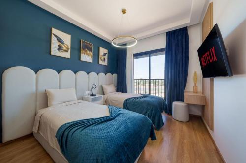 twee bedden in een kamer met blauwe muren bij Belle vue, noria golf in Marrakesh