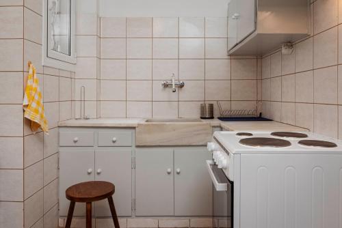 Charming 1Bd apartment in Athens في أثينا: مطبخ أبيض مع موقد ومقعد