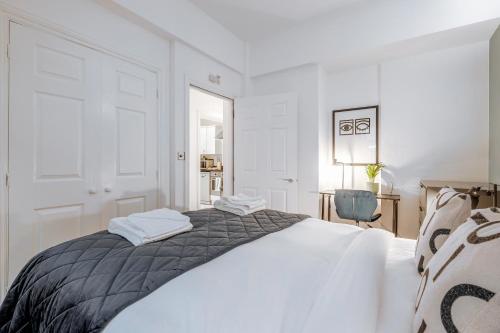 a white bedroom with a bed and a chair at Stay Kula London - Tower Bridge in London