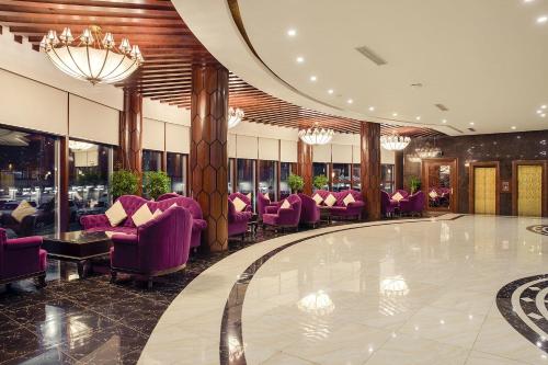 アルビールにあるCristal Erbil Hotelの紫色の椅子とバーのあるホテルロビー