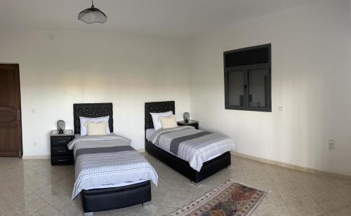 - une chambre avec 2 lits et une télévision murale dans l'établissement Villa Nour Al-Khalil, à Essaouira