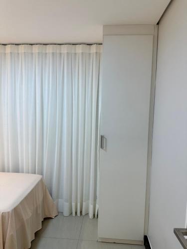 sypialnia z białymi zasłonami i łóżkiem w obiekcie Manhattan Beach Aquiraz Riviera w mieście Aquiraz