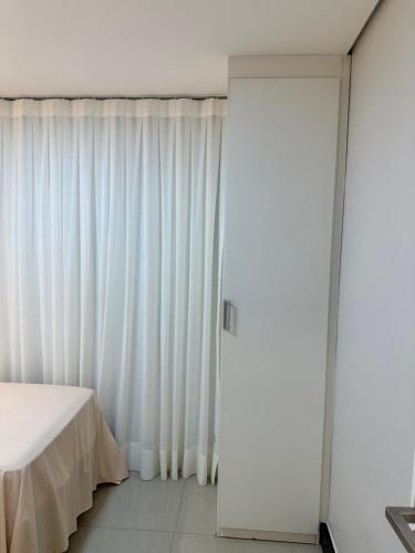 a bedroom with white curtains and a bed at Manhattan Beach Aquiraz Riviera in Aquiraz