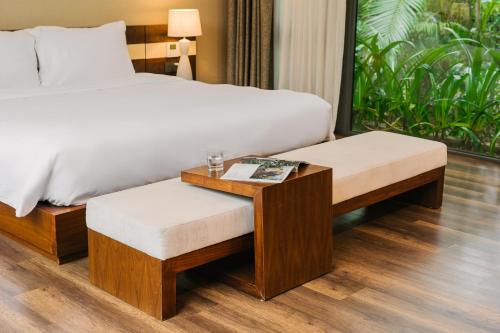 a bedroom with a bed and a table and bench at Rosee Villa - Green Villa with private Pool in Vĩnh Phúc