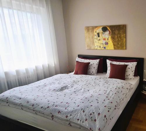 um quarto com uma cama com almofadas vermelhas e uma janela em Appartamento Nadia, bilocale nel verde a 5 minuti dal centro em Merano