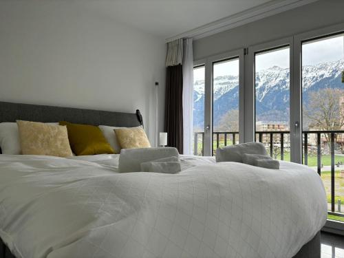 a bedroom with a large white bed with a view of mountains at Center Park in Interlaken