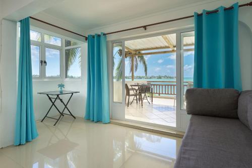 ein Wohnzimmer mit blauen Vorhängen und Meerblick in der Unterkunft LAGOON VIEW Résidence in Grand Baie