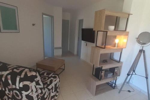 un salon avec un canapé et une télévision dans l'établissement L'Escapade T2 avec Piscine et Jardin, à Saint-Privat