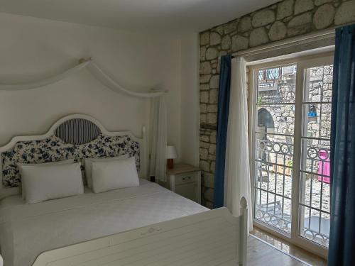 a bedroom with a white bed and a window at Mavi Konak Alaçatı in Alaçatı