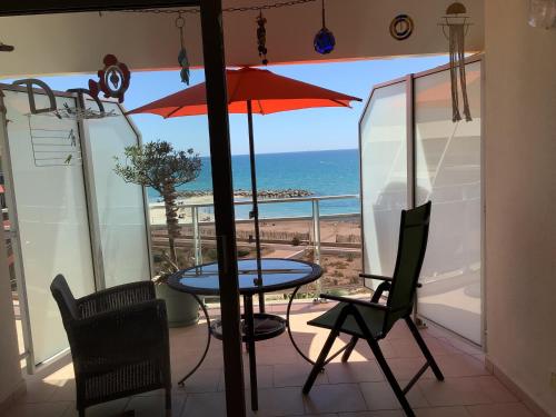 un patio avec une table et des chaises et une vue sur l'océan dans l'établissement VUE MER SOLEIL FARNIENTE TravellerAwards2023, à Palavas-les-Flots