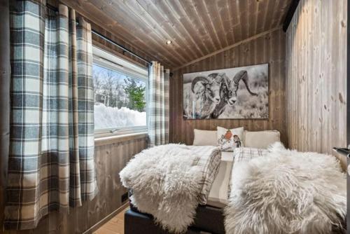 Schlafzimmer mit einem Bett mit pelzigen Kissen und einem Fenster in der Unterkunft Stor familiehytte på Bjorli in Bjorli