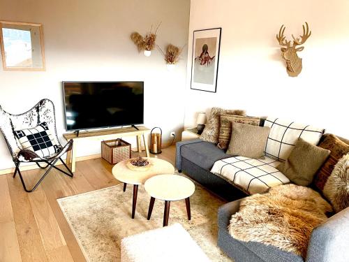 ein Wohnzimmer mit einem Sofa und einem TV in der Unterkunft Window on Crans Montana, Appartement avec vue sur les Alpes in Crans-Montana