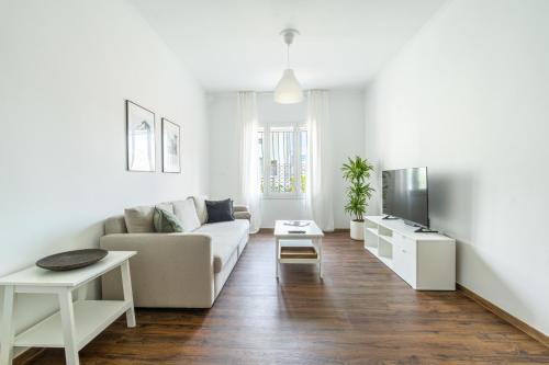 a white living room with a couch and a tv at Superb flat in the historic centre of Athens in Athens