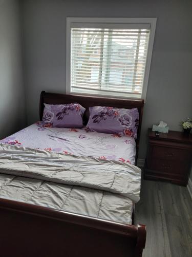 a bedroom with a bed with purple pillows and a window at Individual home in Brampton