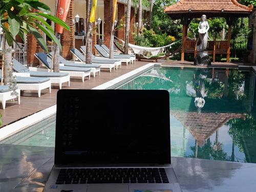 a laptop computer sitting on a table next to a swimming pool at North Wing Canggu Resort in Dalung