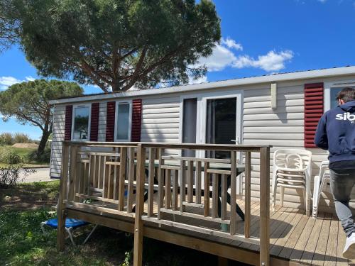 un homme debout sur le pont d'une petite maison dans l'établissement Camping lac des rêves, à Lattes