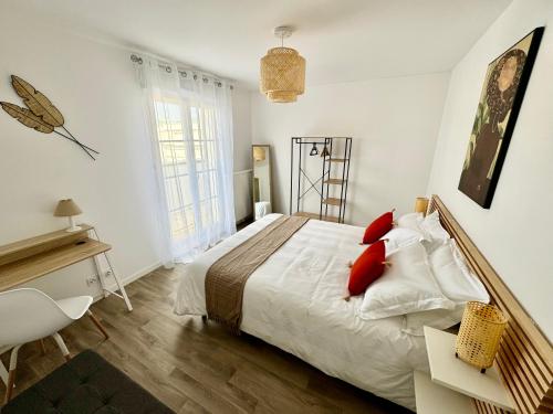 une chambre avec un lit avec des oreillers rouges et un bureau dans l'établissement Le Régence, terrasse, Serris Disney, à Serris