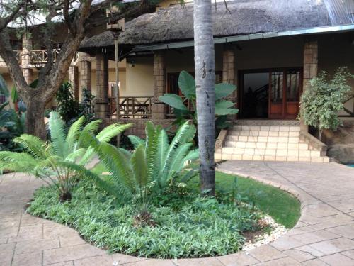 a garden in front of a building with a palm tree at Prinshof Manor Guesthouse in Pretoria