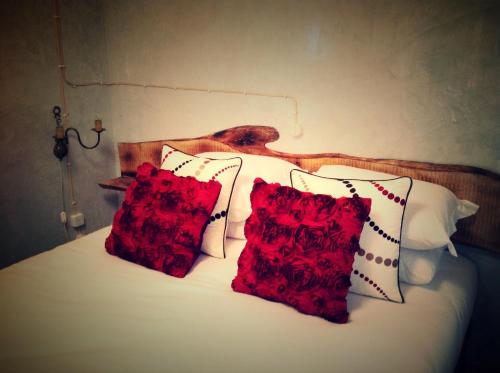 a bed with two red pillows on it at Aldeia Dos Caldeirões in São Mateus
