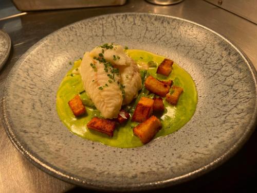 a plate of food with fish and potatoes on a table at Five Alls in Lechlade