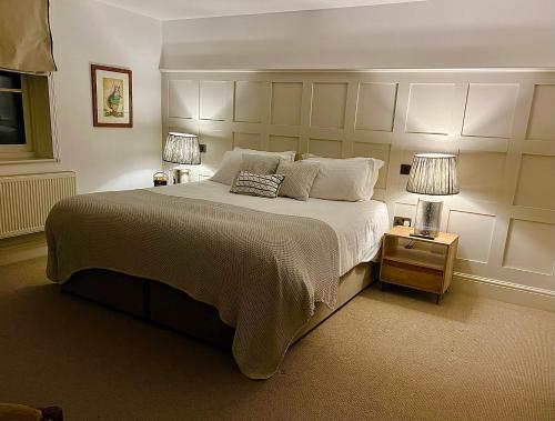 a bedroom with a large bed and two lamps on tables at Five Alls in Lechlade