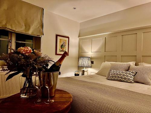 a bedroom with a bed with a bottle of wine and flowers at Five Alls in Lechlade