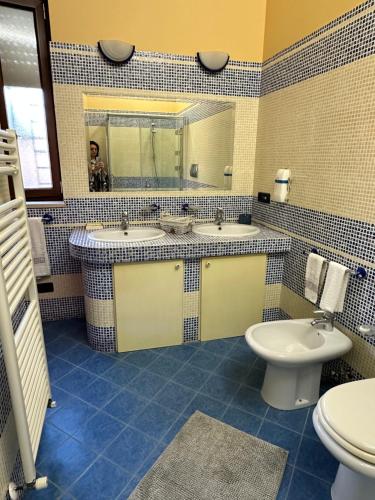 een badkamer met 2 wastafels, een toilet en een spiegel bij VerdeMareVilla in Avola