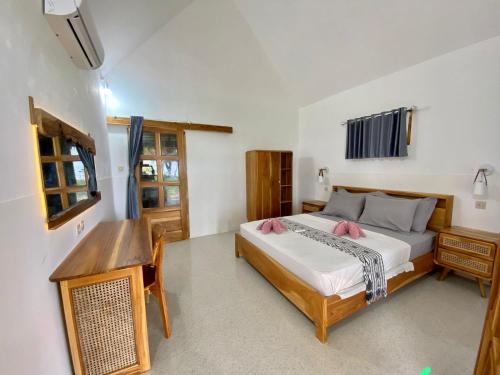 a bedroom with a bed and a desk in it at Abdi Fantastik in Gili Air