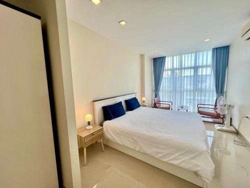 a bedroom with a white bed and a large window at Chez Wanida - apartment Krabi in Klong Muang Beach