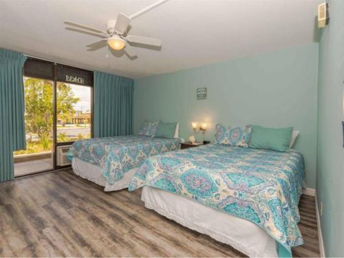 a bedroom with two beds and a ceiling fan at Benjamin's Pier at Laguna Reef Resort in Rockport