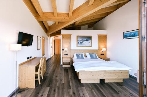 Schlafzimmer mit einem Bett, einem Schreibtisch und einem TV in der Unterkunft Chalet Caminetto in Vason