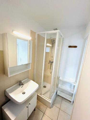 une salle de bain blanche avec un lavabo et une douche dans l'établissement maison indépendante très calme RER A, à Montesson