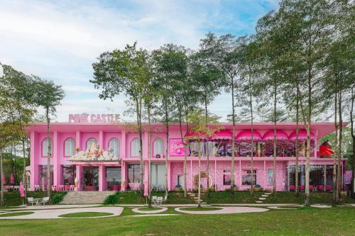 a pink building in front of a park at Rosee Villa - Green Villa with private Pool in Vĩnh Phúc