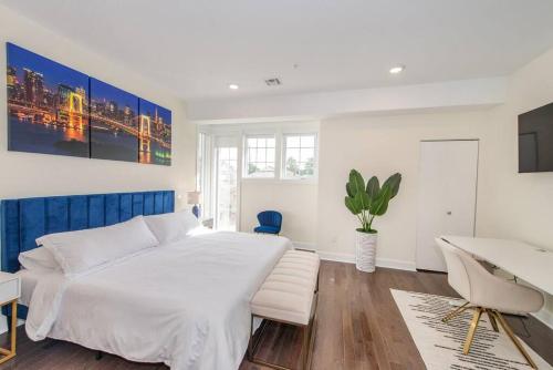 a white bedroom with a large bed and a desk at Chic Condo-NYC@Fingertips in North Bergen