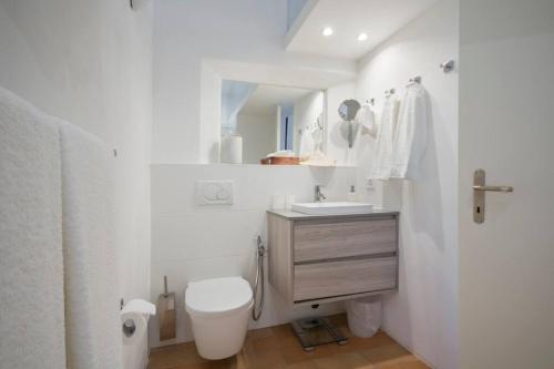 a white bathroom with a toilet and a sink at Charming apartment w/courtyard in historical house in Lugano
